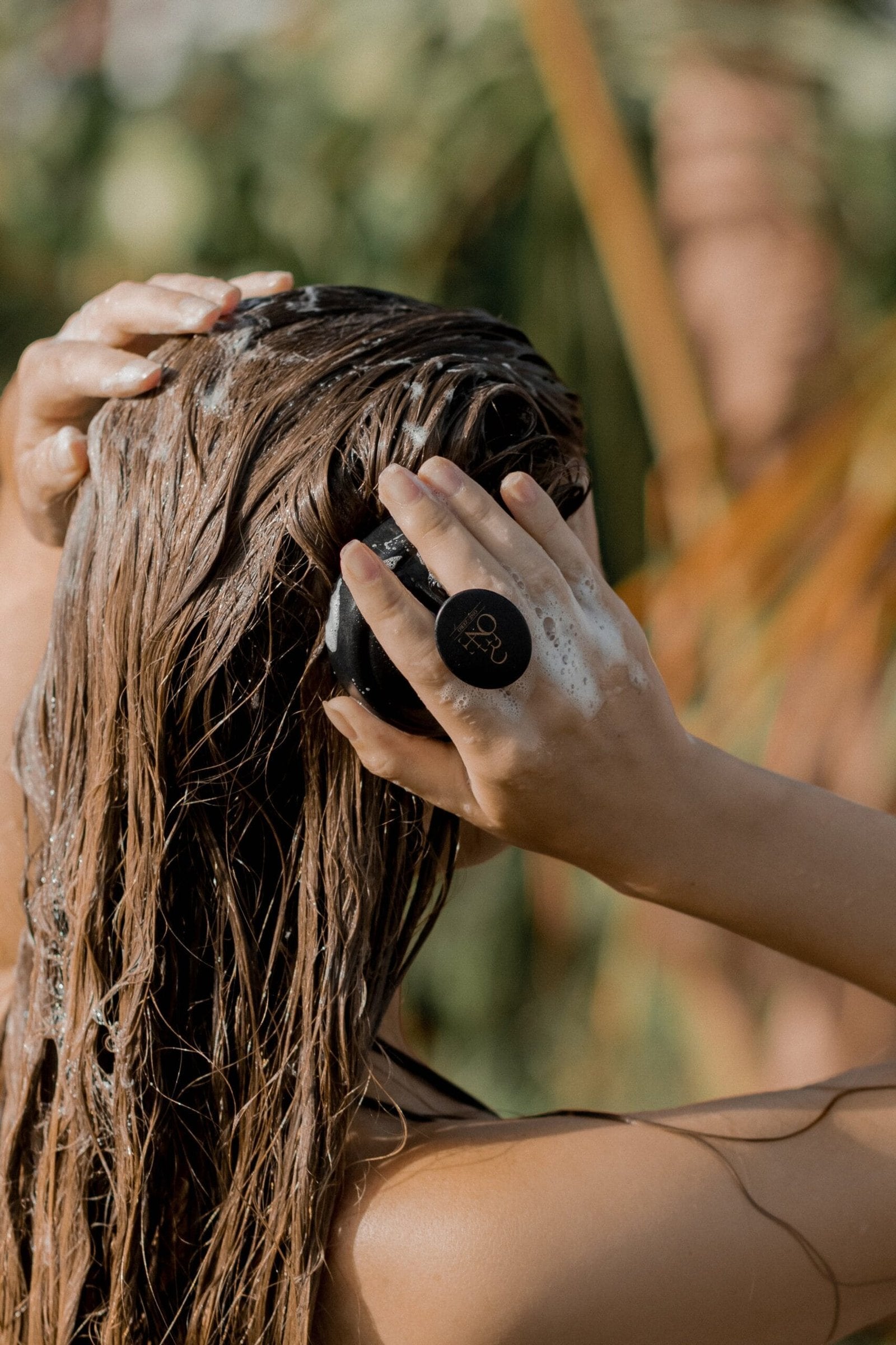 A woman washes her hair with a scalp massage brush