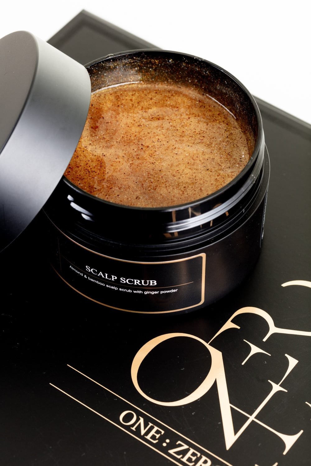 An open jar with ginger-textured scalp scrub