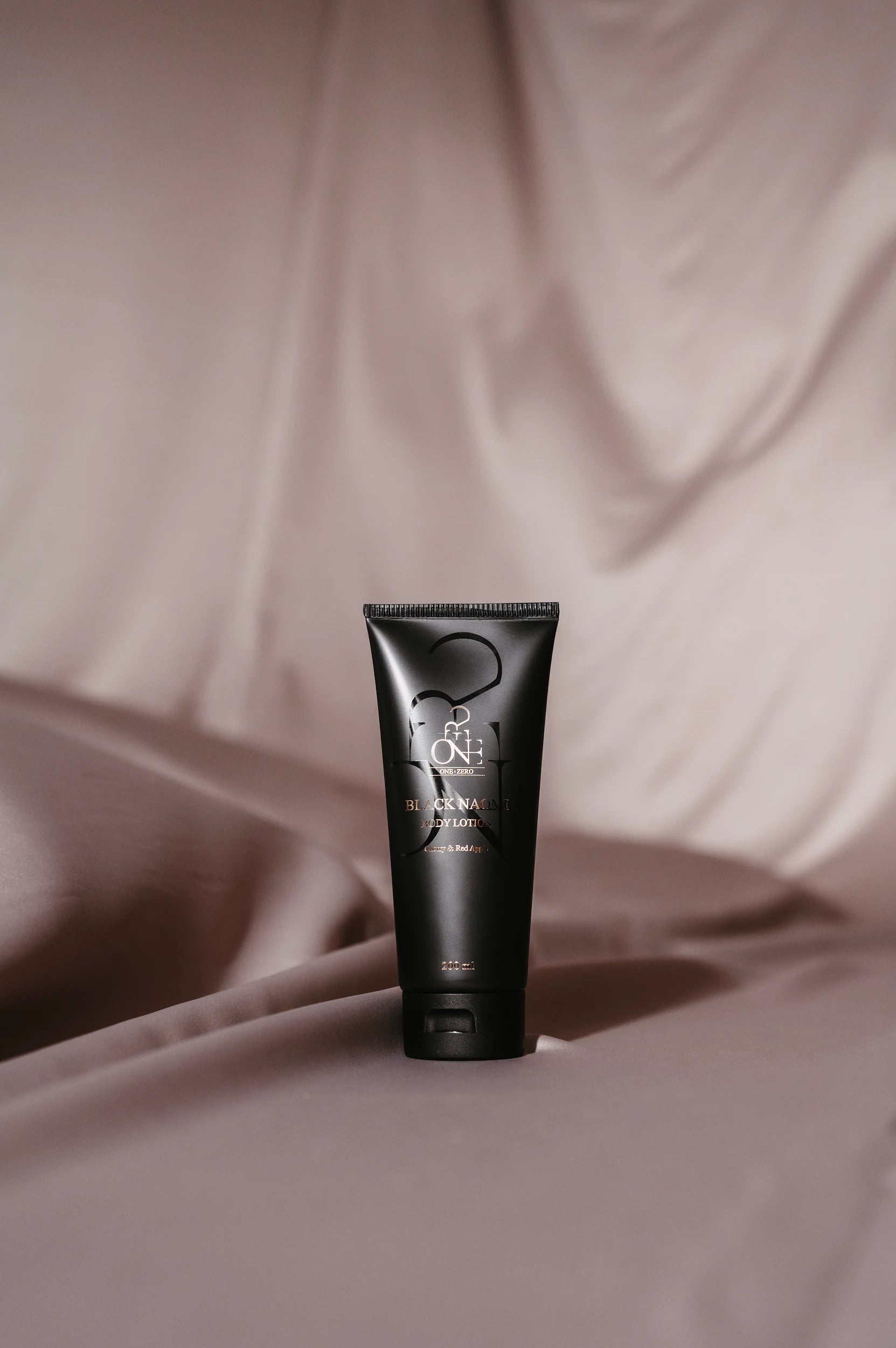 Body lotion "Black Naomi" on pinkish grey silk