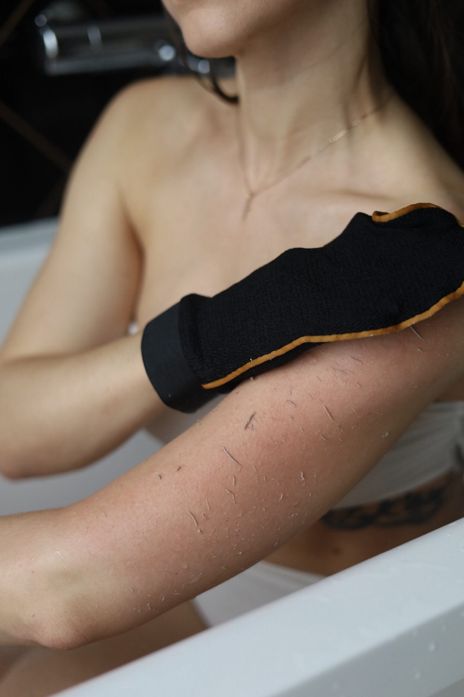 A man in the bath treats his arm with an scrub glove